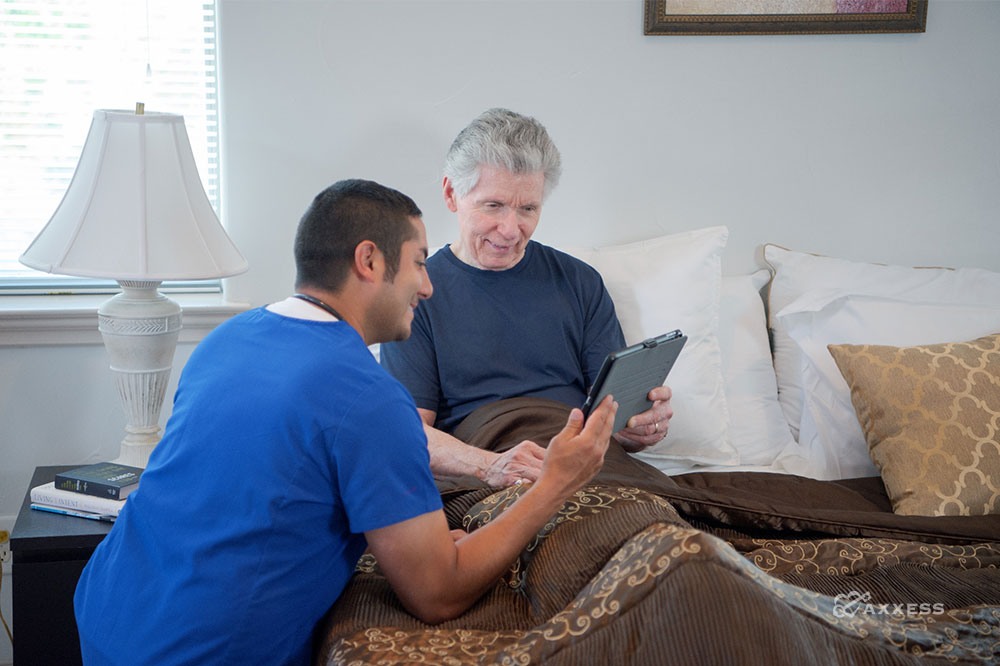 a clinician showing a tablet to a patient in bed