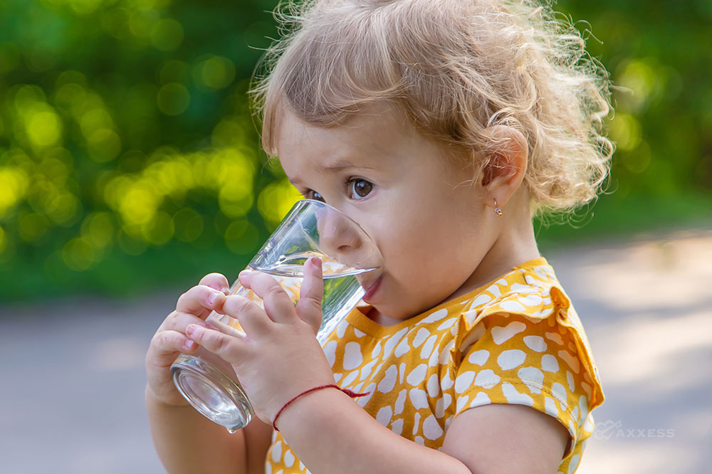 Young girl drinks a glass of water outside