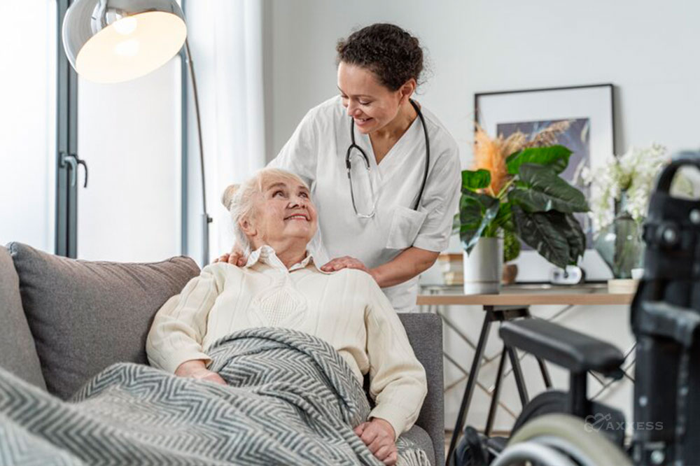 An elderly woman receives care from a female clinician in her home.