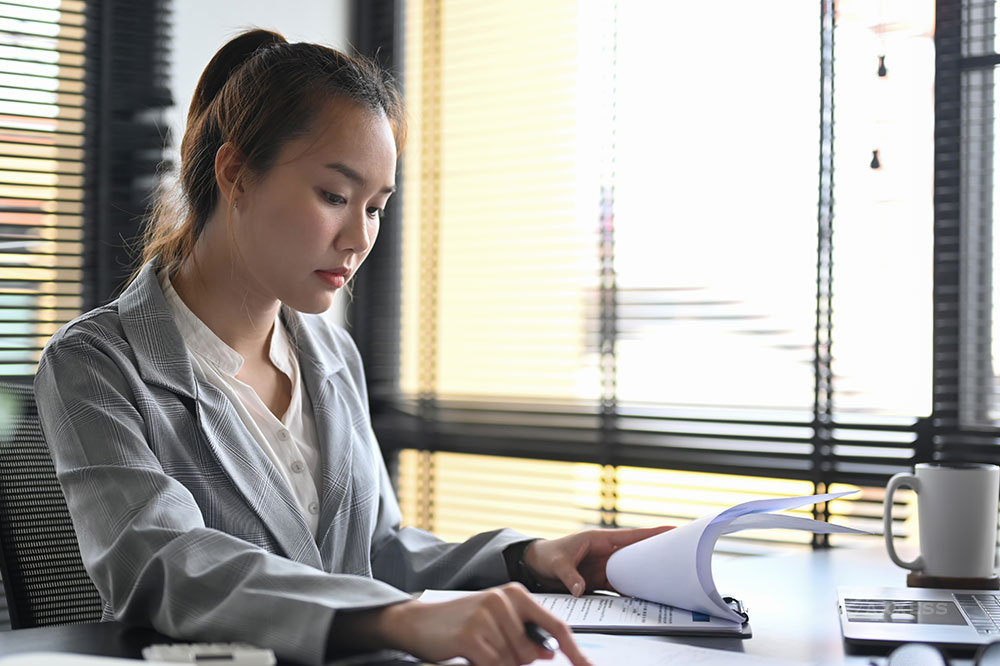 Female operational leader reviews data in a clipboard at her desk