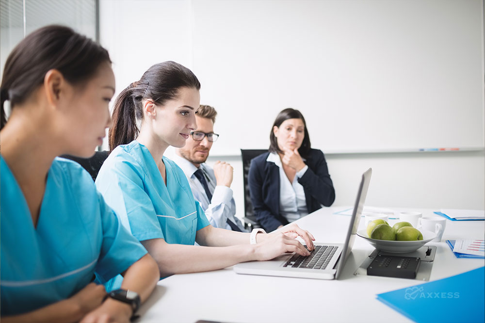 Three female and one male clinician gather and look at a laptop together