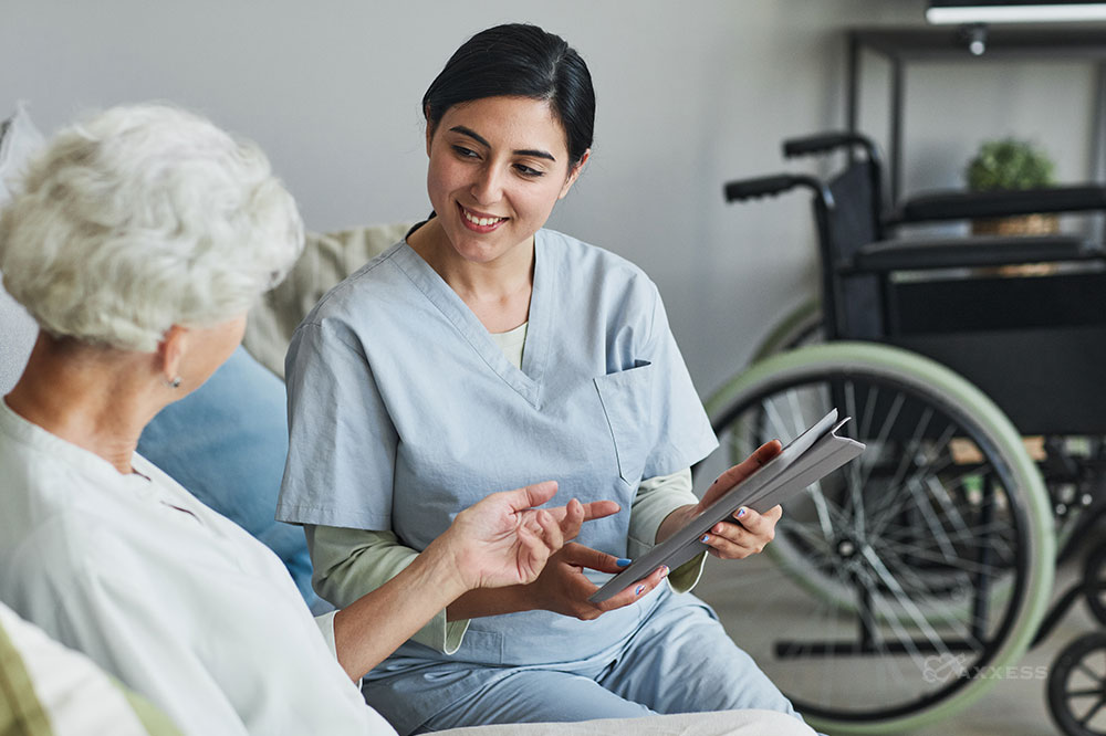 A female clinicians holds a tablet while speaking with an elderly client.