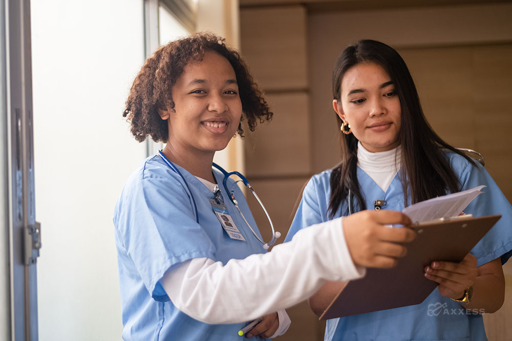 Two female nurses hold a clipboard