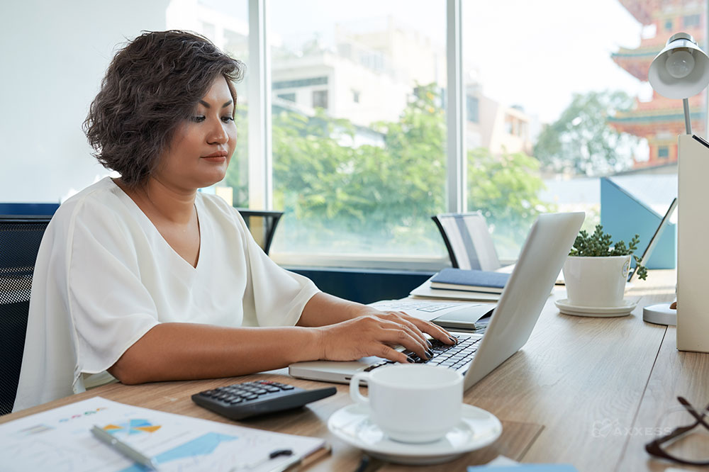 A female with short brown hair sits at a desk using a laptop