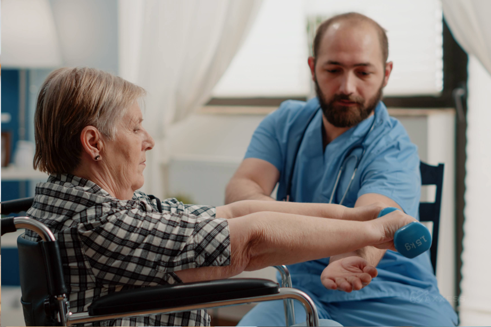 A physical therapist helps a senior woman in a wheelchair do arm exercises with a dumbbell.