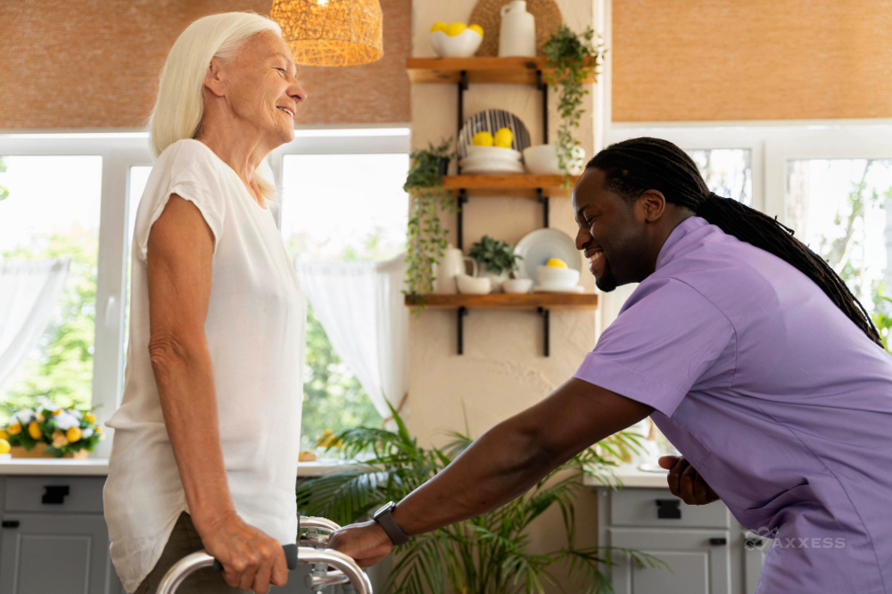 A caregiver, in a lavender medical shirt, aids a senior woman with a gentle smile, navigating the contemporary kitchen with a walker.